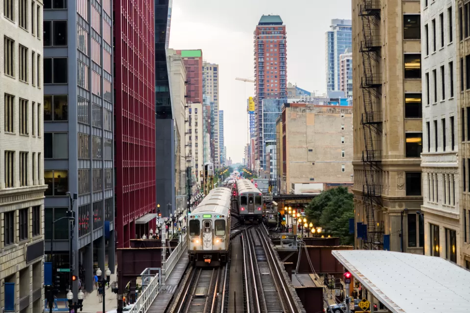 Two Chicago elevated trains with city buildings in background